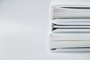 En stack med vita mappar och dokument för ansökan om företagskredit.