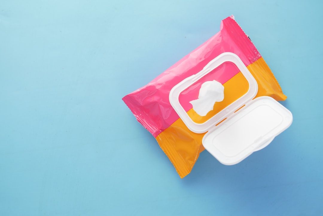 Ett paket våtservetter i rosa och orange förpackning på blå bakgrund.